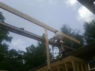 Carpenter setting a ridge beam over a new addition frame — Ice Dam Removal by Roofing Brothers in South Heart