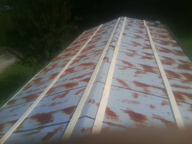 Rusted metal roof panels with new wood purlins before replacement — Storm Damage Roof Repair in South Heart by Roofing Brothers
