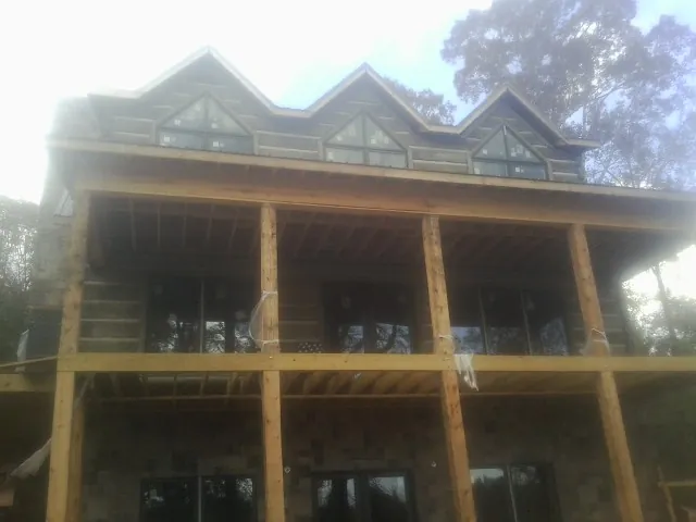 Dormers and porch framing on a large log home under construction — Roof Coating work by our crew in South Heart