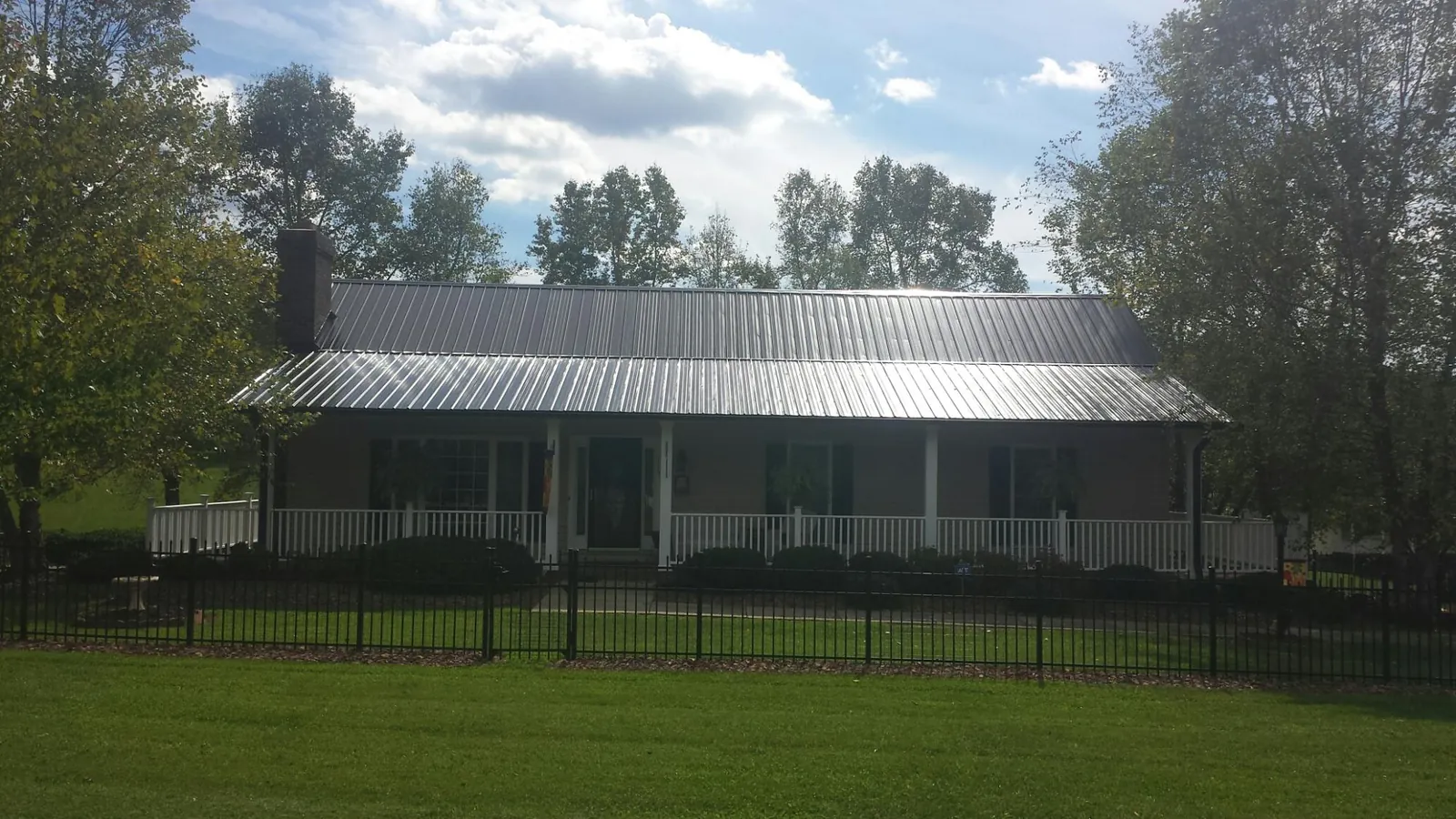 Gray metal roof on a brick ranch with a full width front porch — Gutter Guard Installation work by our crew in South Heart