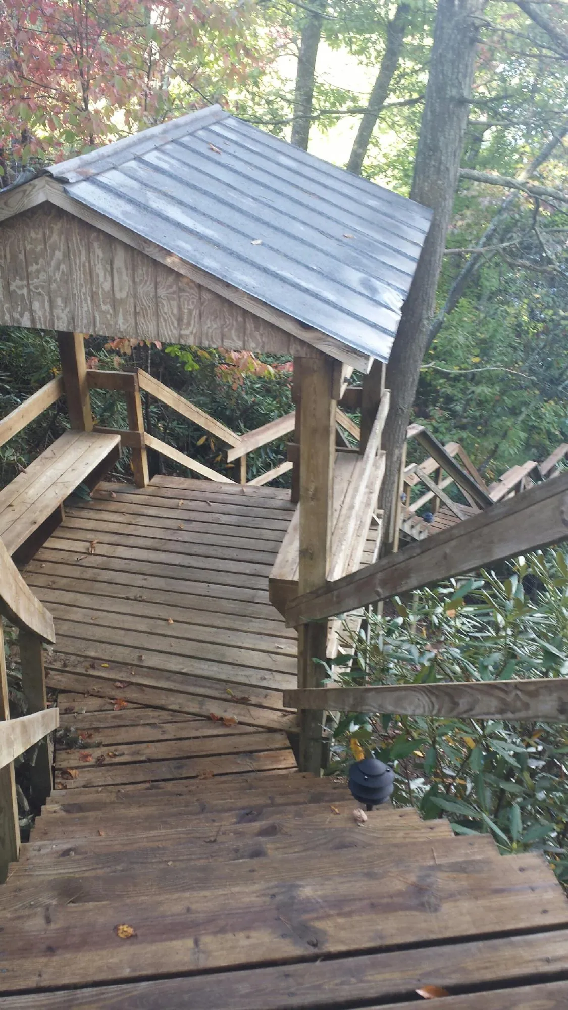 Metal roofed shelter over wooden steps on a wooded walkway — Skylight Repair & Installation work by our crew in South Heart
