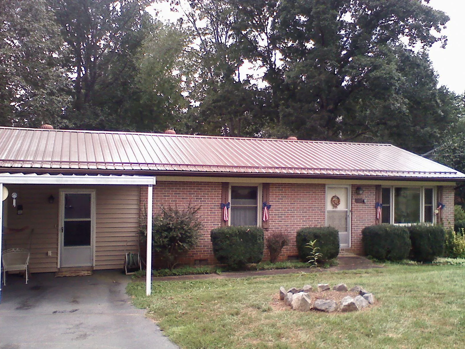 Bronze metal roof and carport on a brick ranch home — Roof Repair work by our crew in South Heart