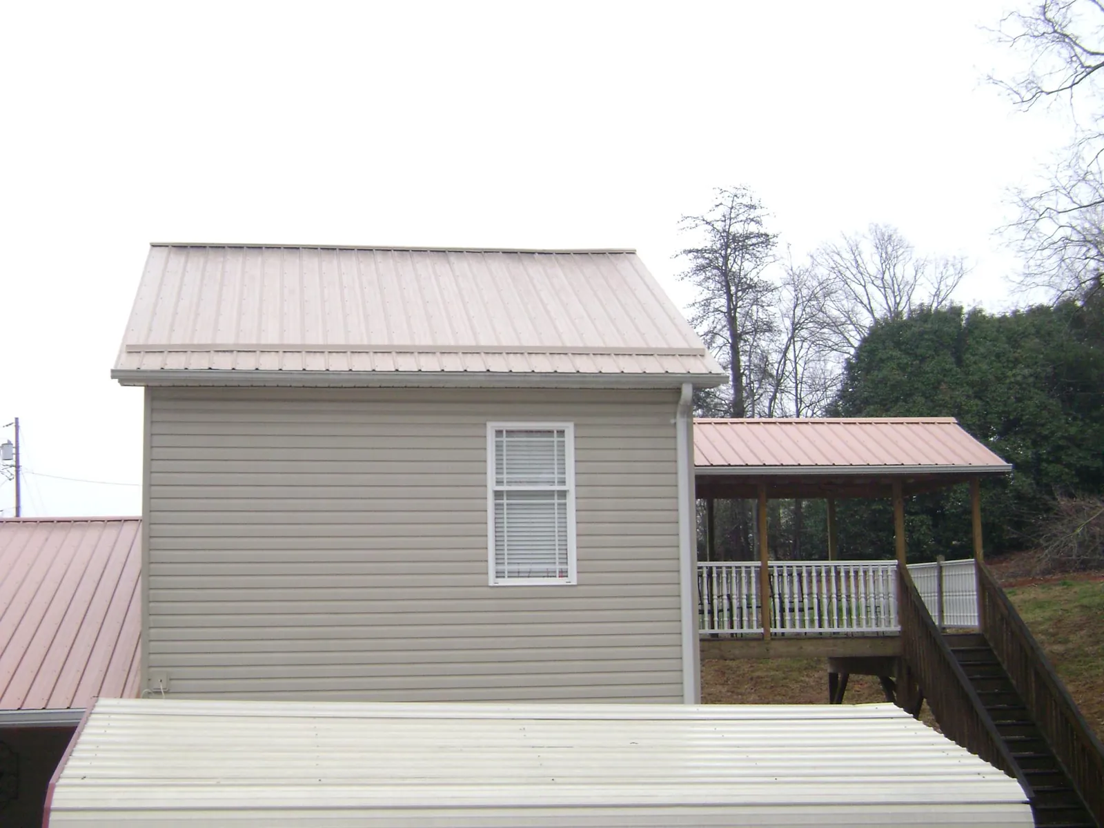 Tan metal roofs on a two story addition and attached porch, from a Roof Replacement job in South Heart