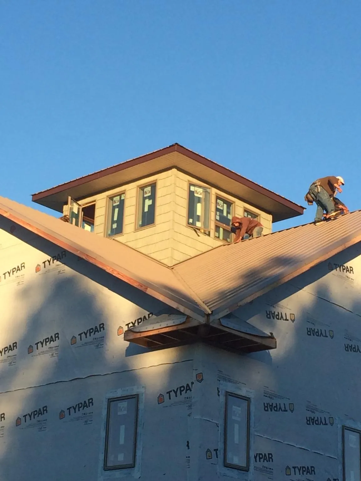 Roofers working around a rooftop cupola on a new metal roof at sunset — Roof Waterproofing in South Heart by Roofing Brothers